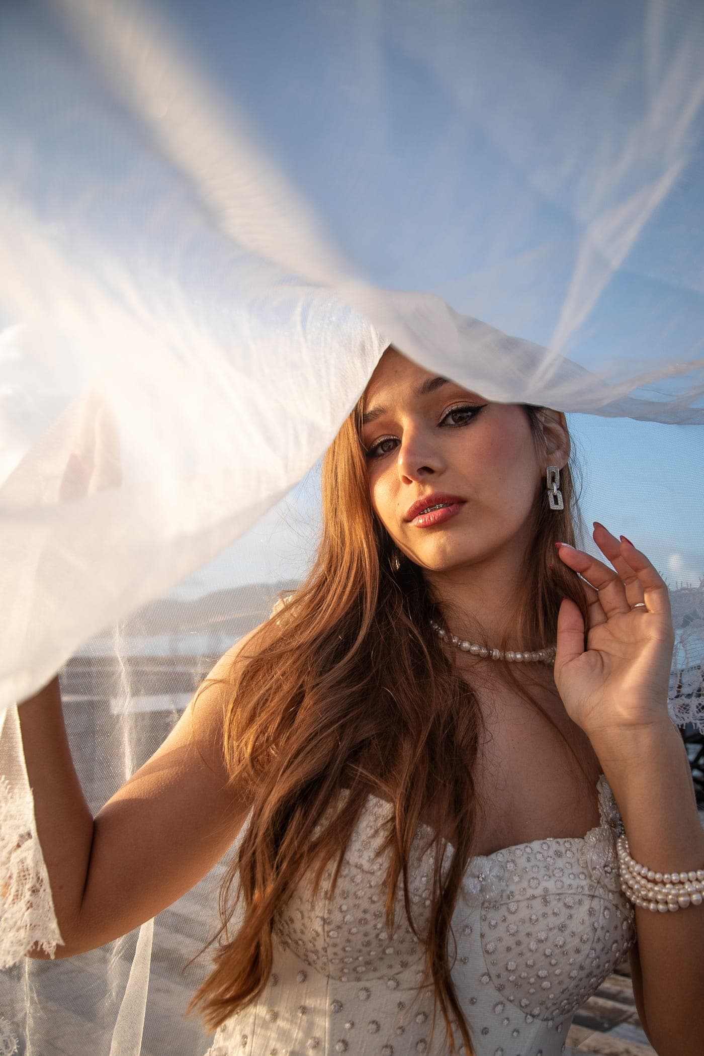 Veil lifted across the face, backlit by the low sun