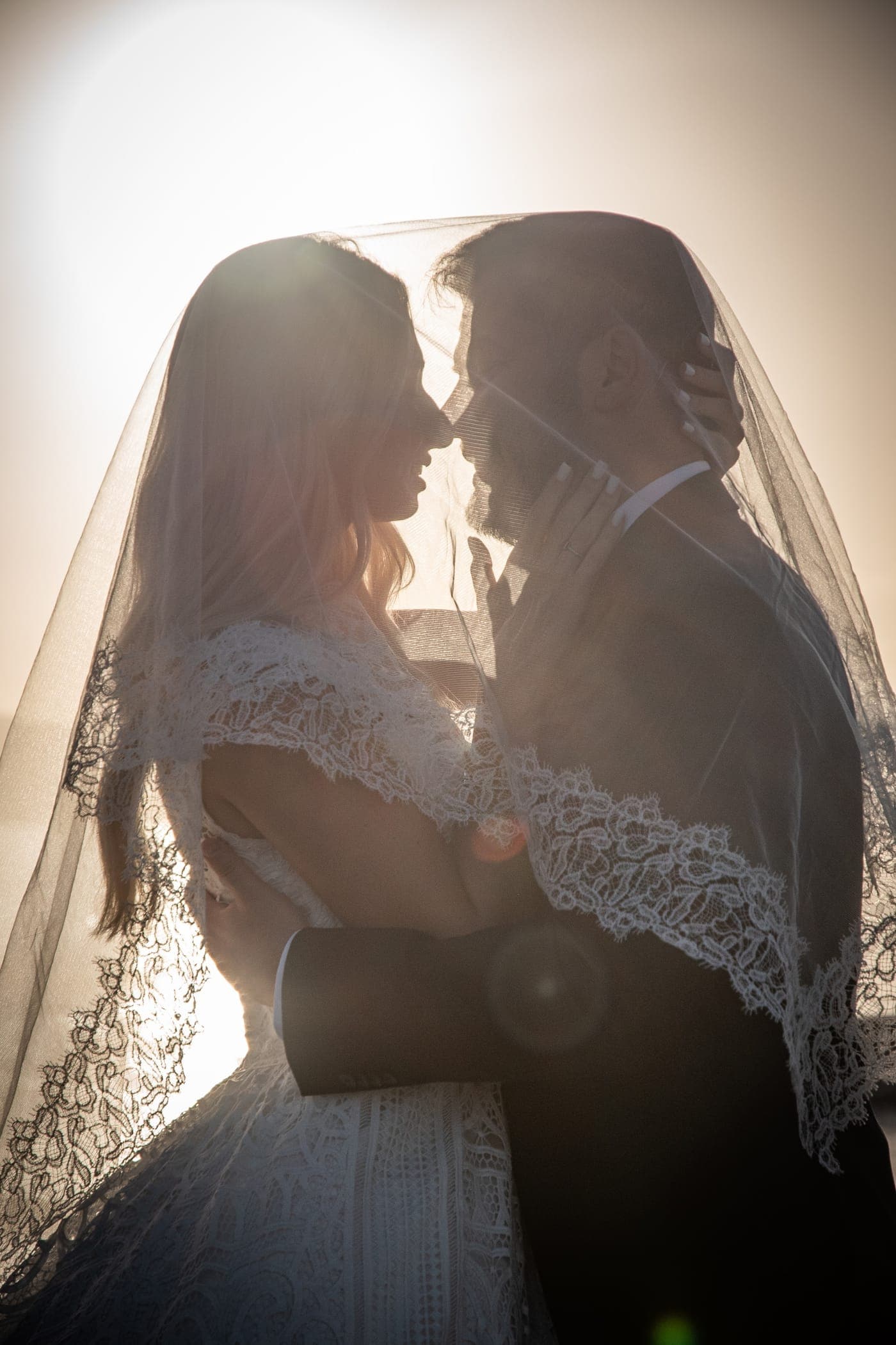 Bride and groom beneath the veil at sunrise