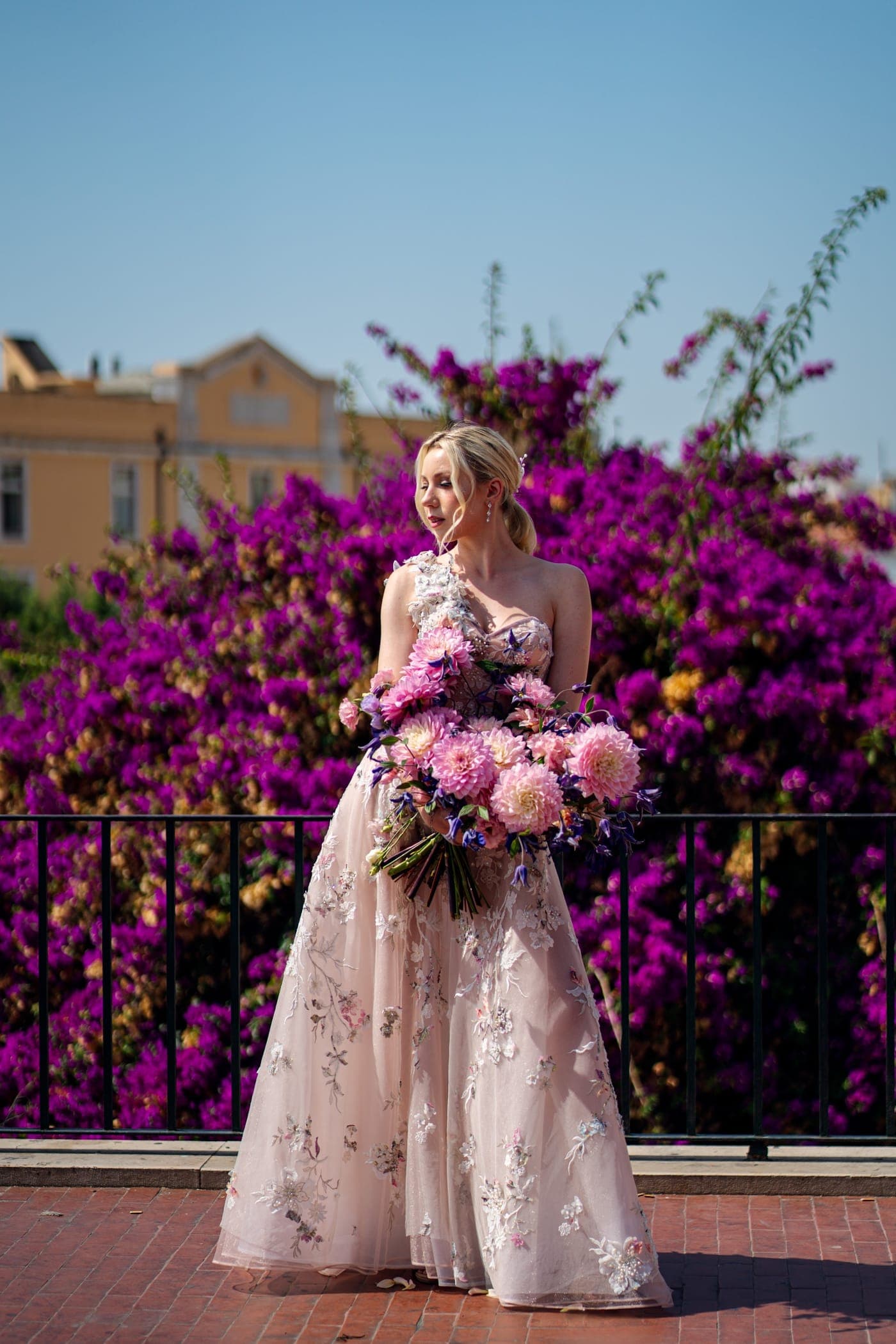 A blush gown in hand-applied florals against bougainvillea in Lisbon