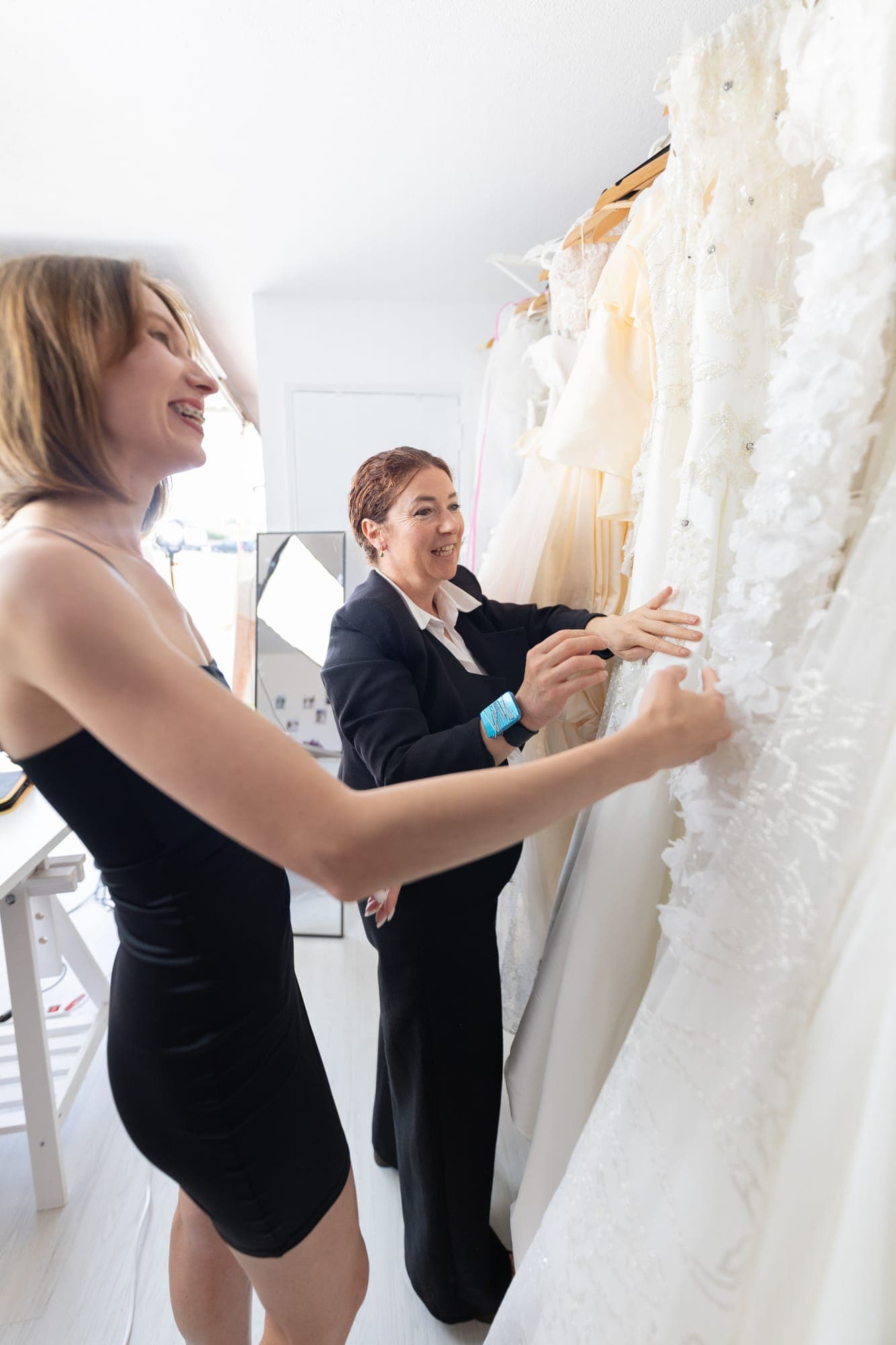 A bride and a bridal consultant looking through a rail of lace wedding gowns together in a boutique