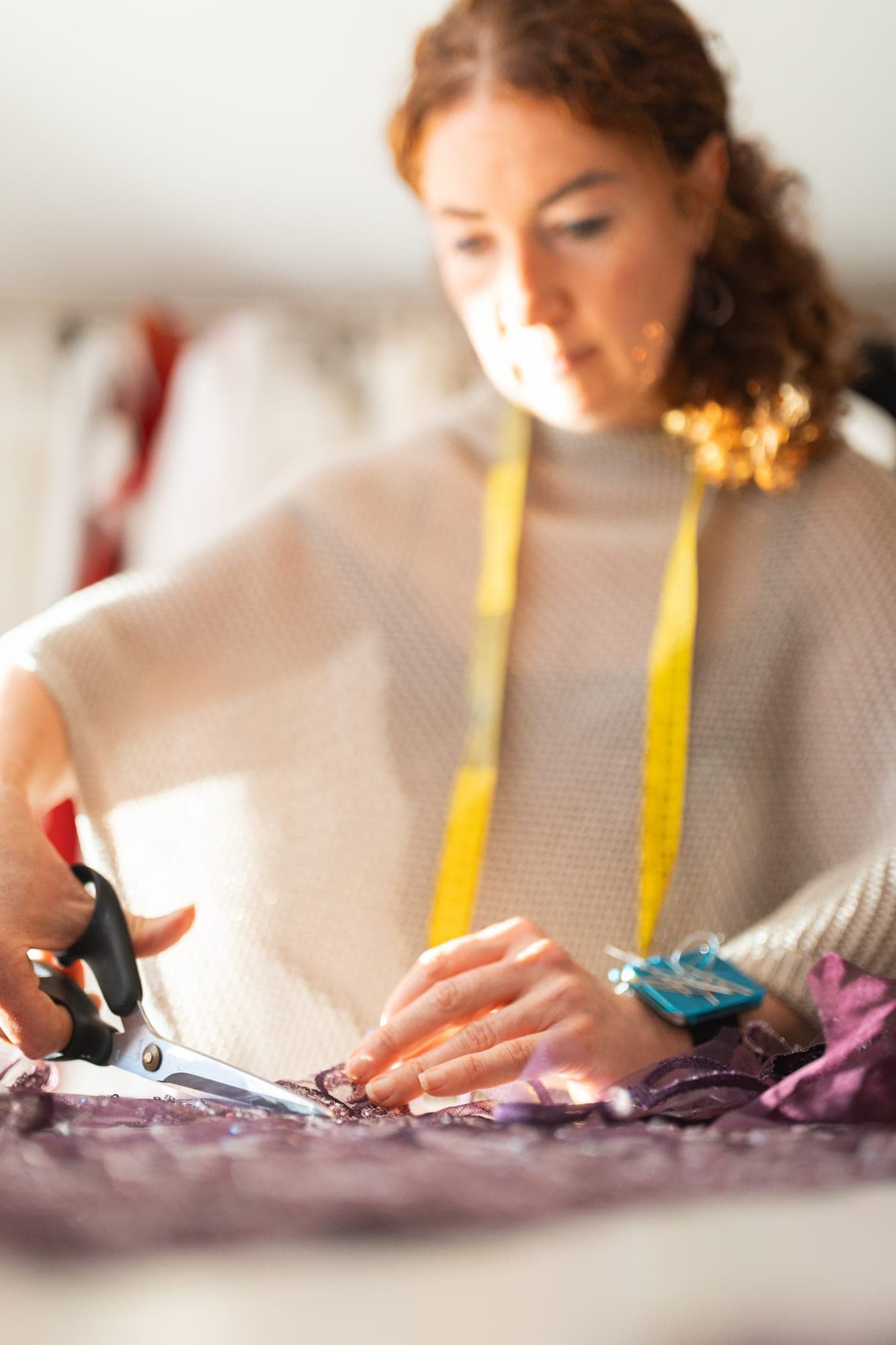 Seamstress threading a needle at an atelier workbench
