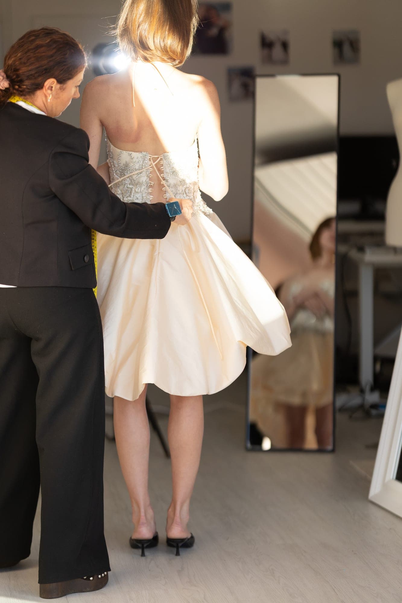 Fitter lifting the tulle skirt of a short dress to check its volume