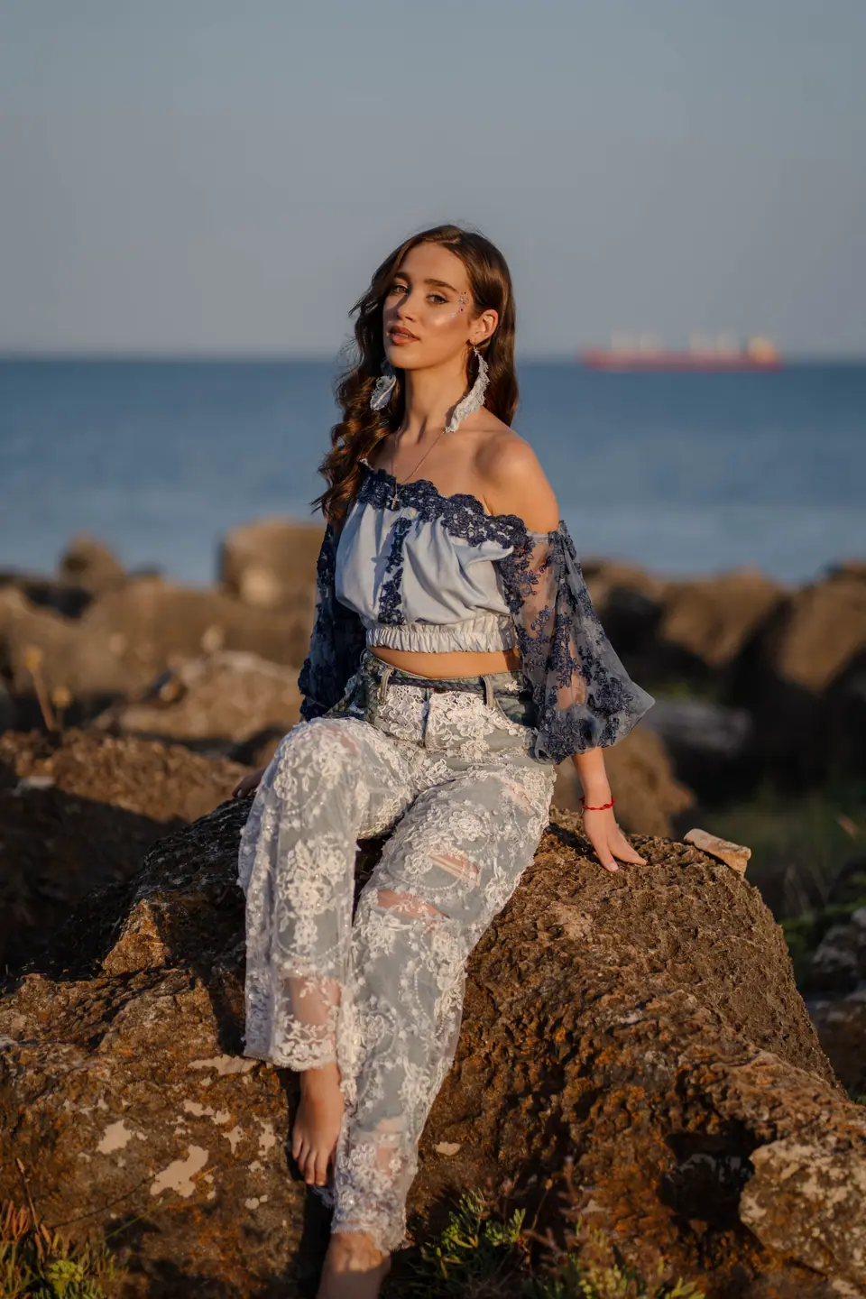 Two models in lace and denim on the rocks at sunrise