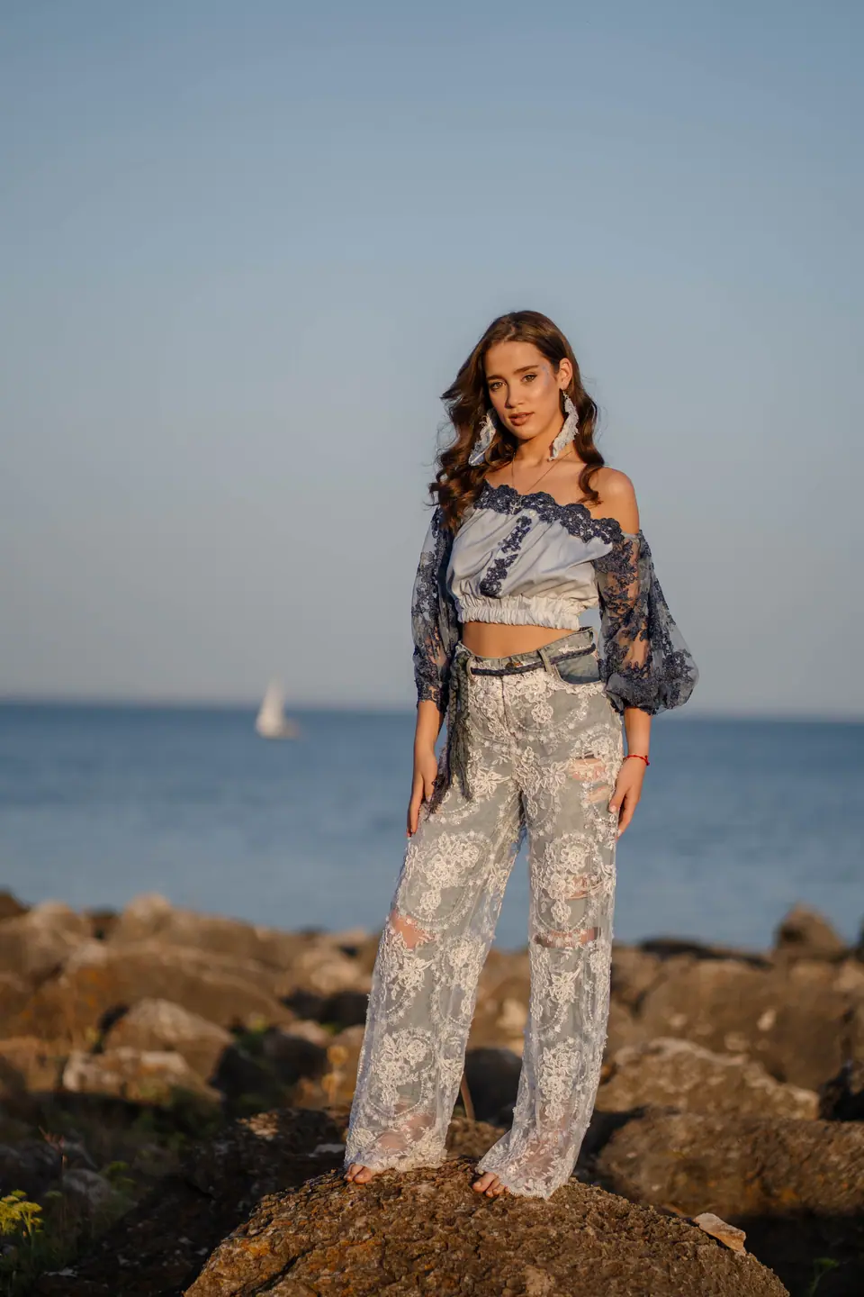 Two models in lace and denim on the rocks at sunrise