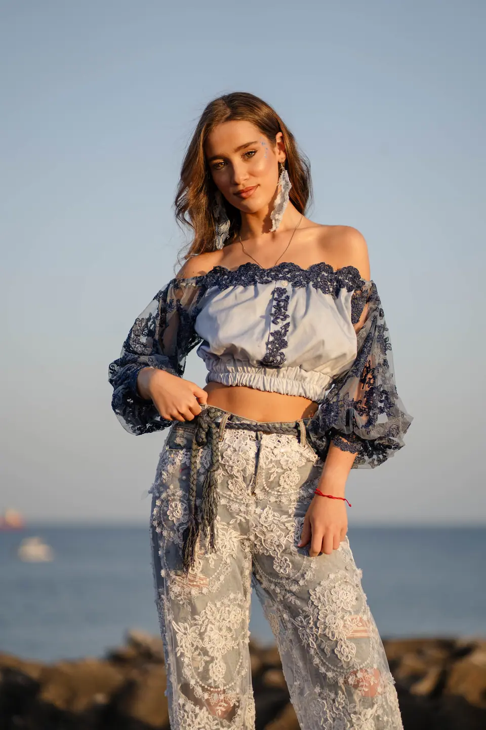 Two models in lace and denim on the rocks at sunrise