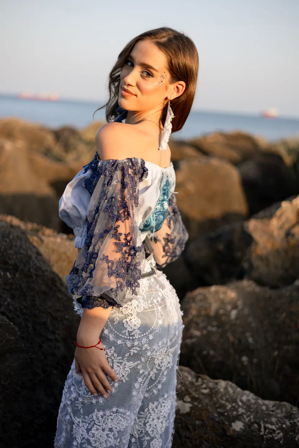 Two models in lace and denim on the rocks at sunrise