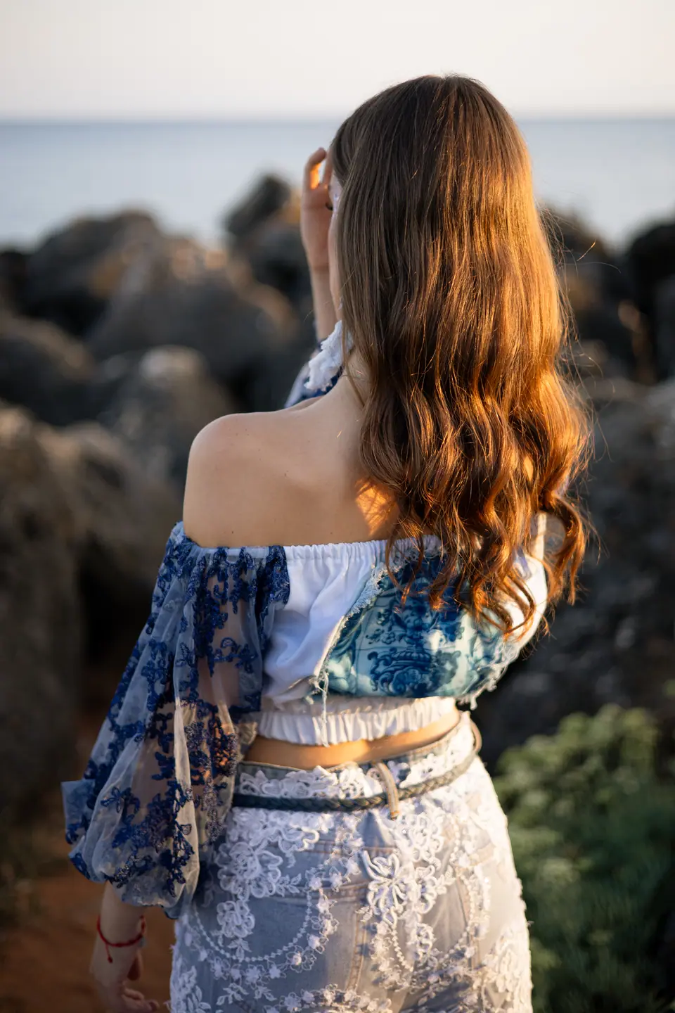 Two models in lace and denim on the rocks at sunrise