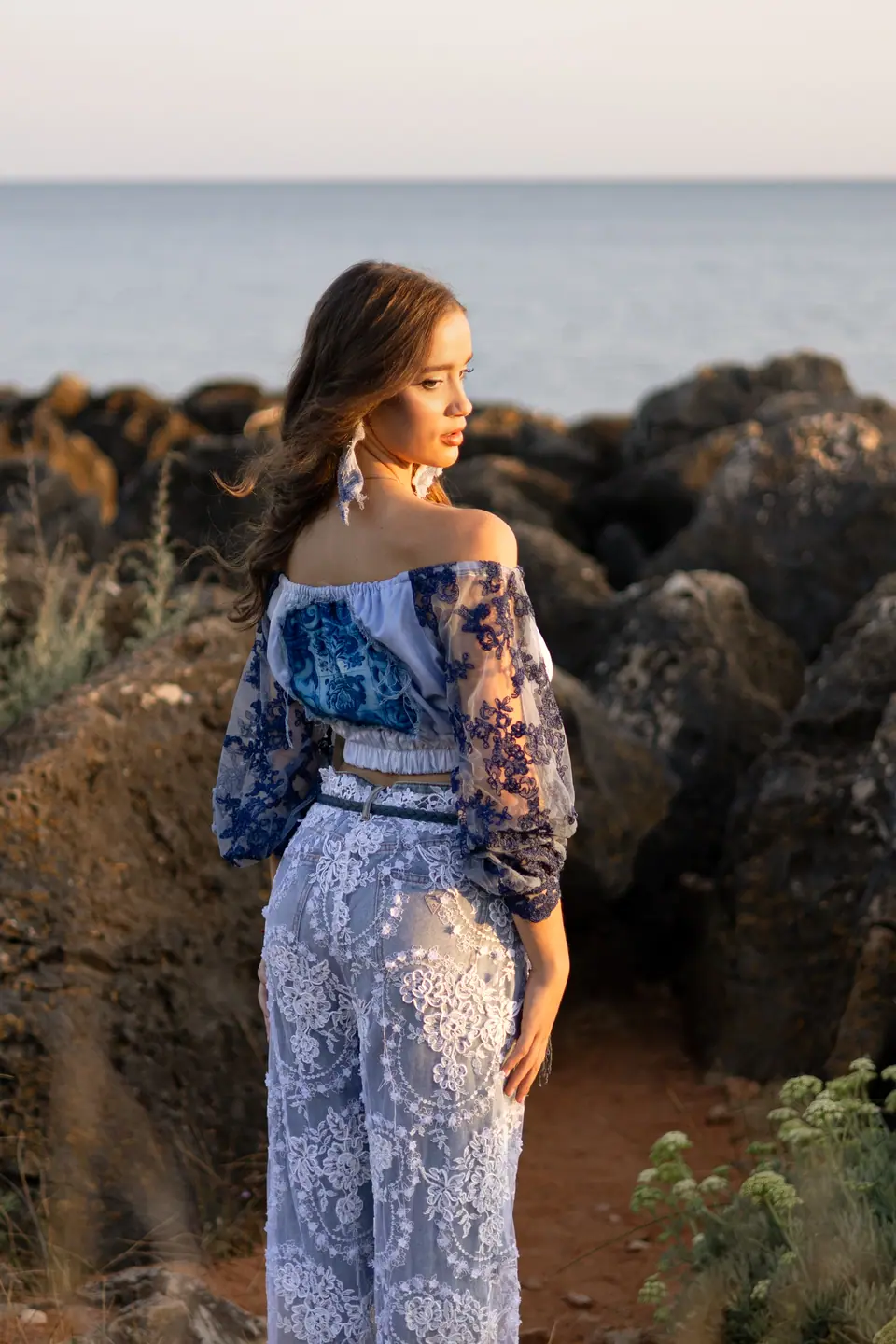 Two models in lace and denim on the rocks at sunrise